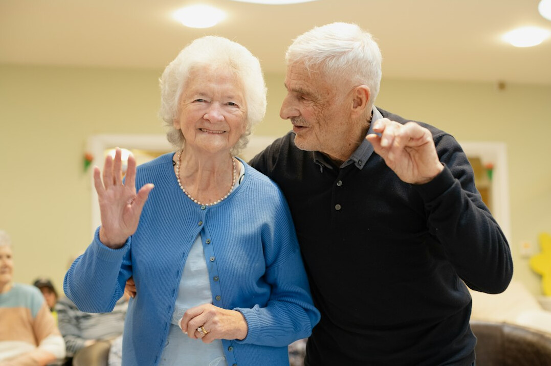 elderly couple holding hands at home